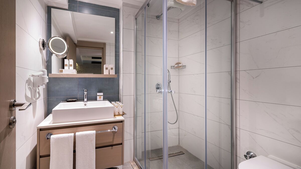 A modern bathroom with a glass-enclosed shower, a vanity with a mirror, and a towel rack.