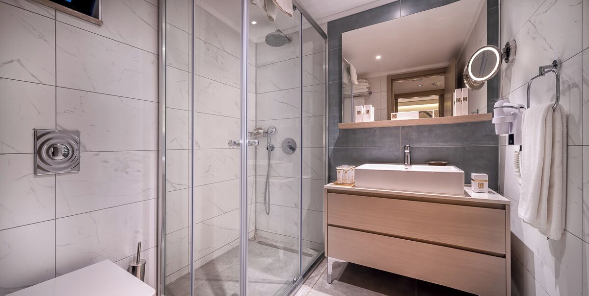 Une salle de bain moderne avec une douche à parois de verre, un meuble-lavabo en bois avec un miroir et un lavabo blanc.