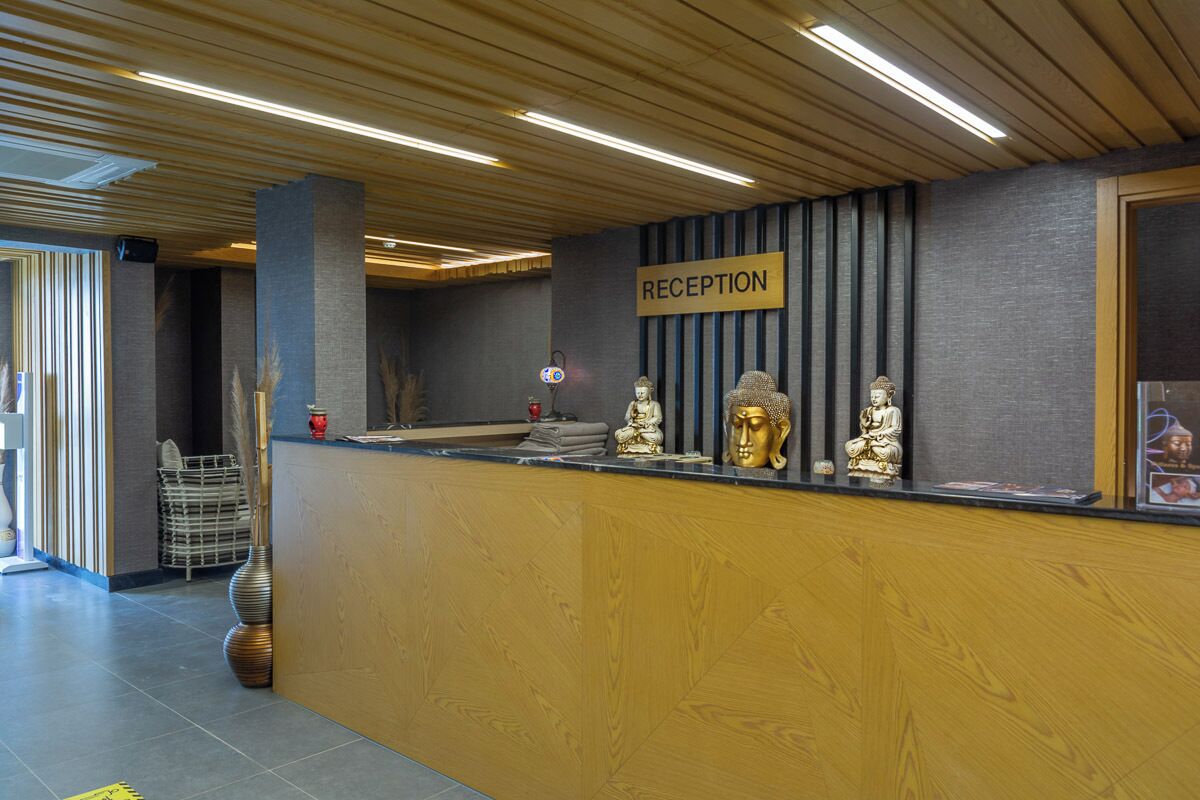 A reception area with a wooden reception desk, a 'RECEPTION' sign, and several Buddha statues.