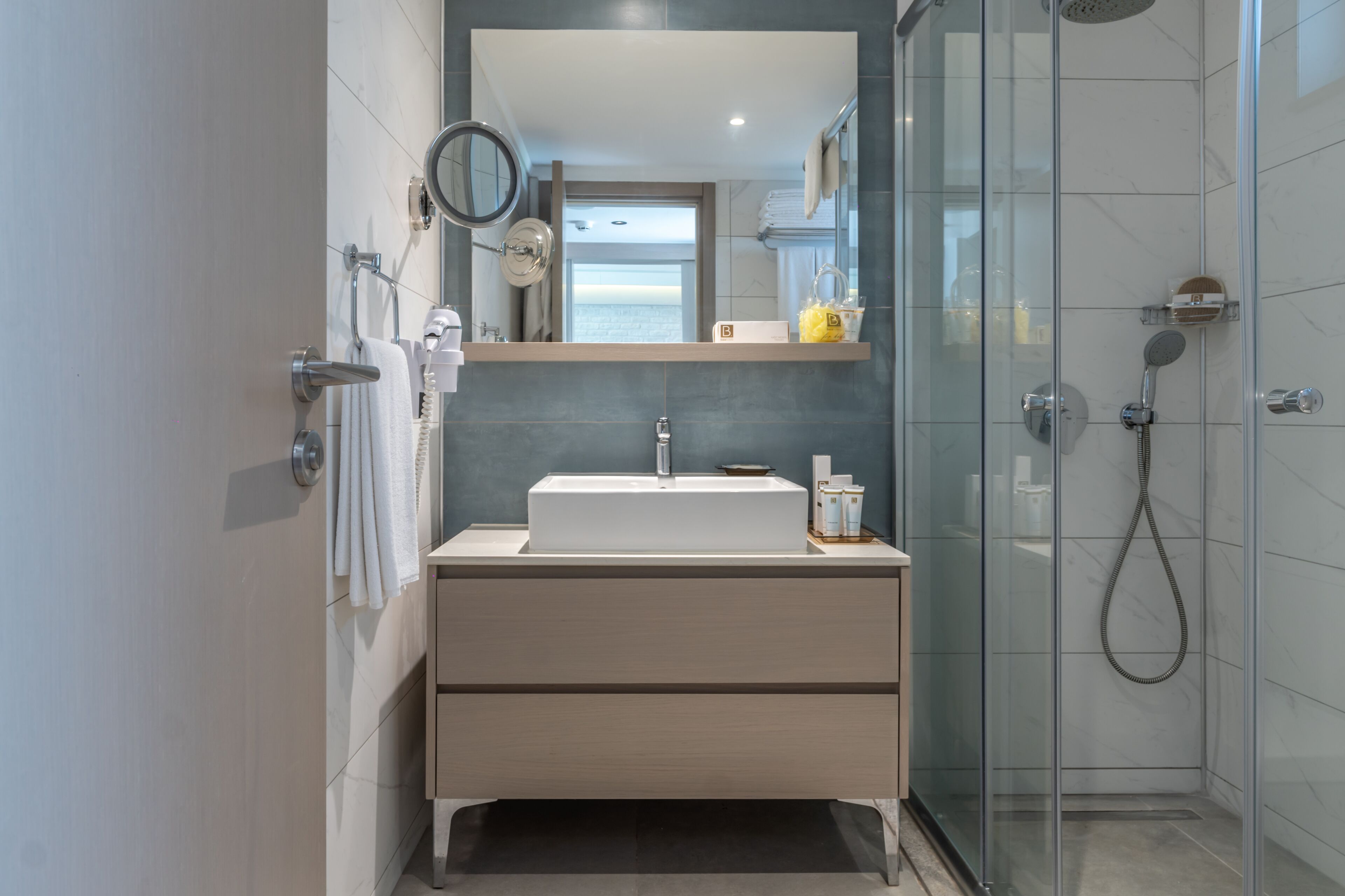 Un baño moderno con cabina de ducha de vidrio, un lavamanos blanco y un espejo encima.