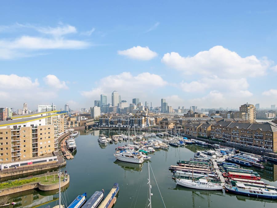 Una marina con barcos amarrados, rodeada de edificios y un horizonte urbano al fondo.
