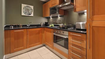 Une cuisine moderne avec des meubles en bois, des appareils électroménagers en acier inoxydable et un sol carrelé.