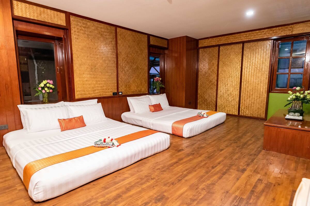 Quarto de hotel com duas camas, piso de madeira e parede verde.