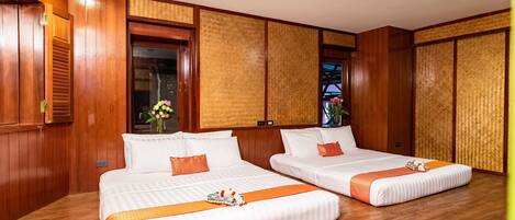 A hotel room with two beds, wooden flooring, and a large window with a view.