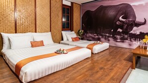 Quarto de hotel com duas camas, painéis de madeira, um grande mural de um búfalo e piso de madeira.
