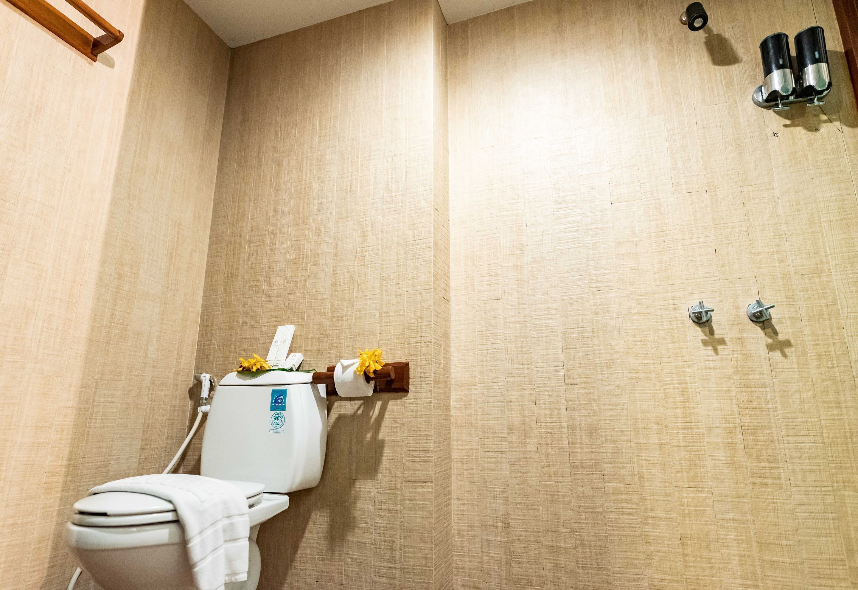 Une salle de bain équipée de toilettes, d’une serviette et d’un porte-rouleau de papier toilette.