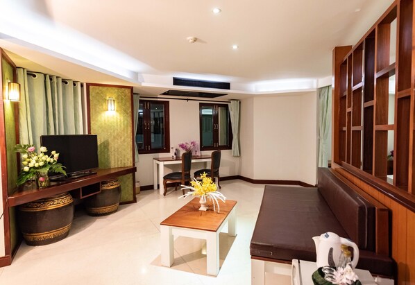 A modern living room with a flat-screen TV, a wooden bench, a dining table with chairs, and decorative vases. - Dang Derm Khaosan (Bangkok)