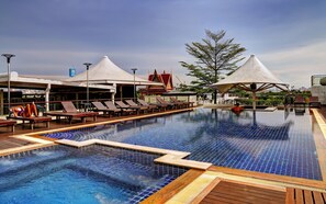 A swimming pool with lounge chairs and umbrellas, surrounded by a wooden deck and a building with a traditional roof. - Dang Derm Khaosan (Bangkok)