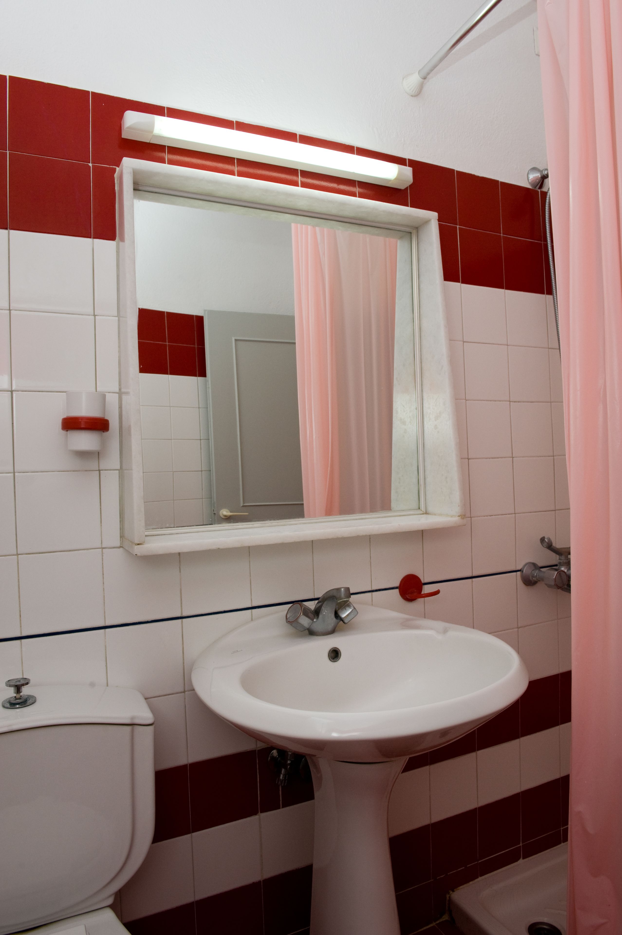 Une salle de bain avec un lavabo blanc, un miroir et des toilettes.