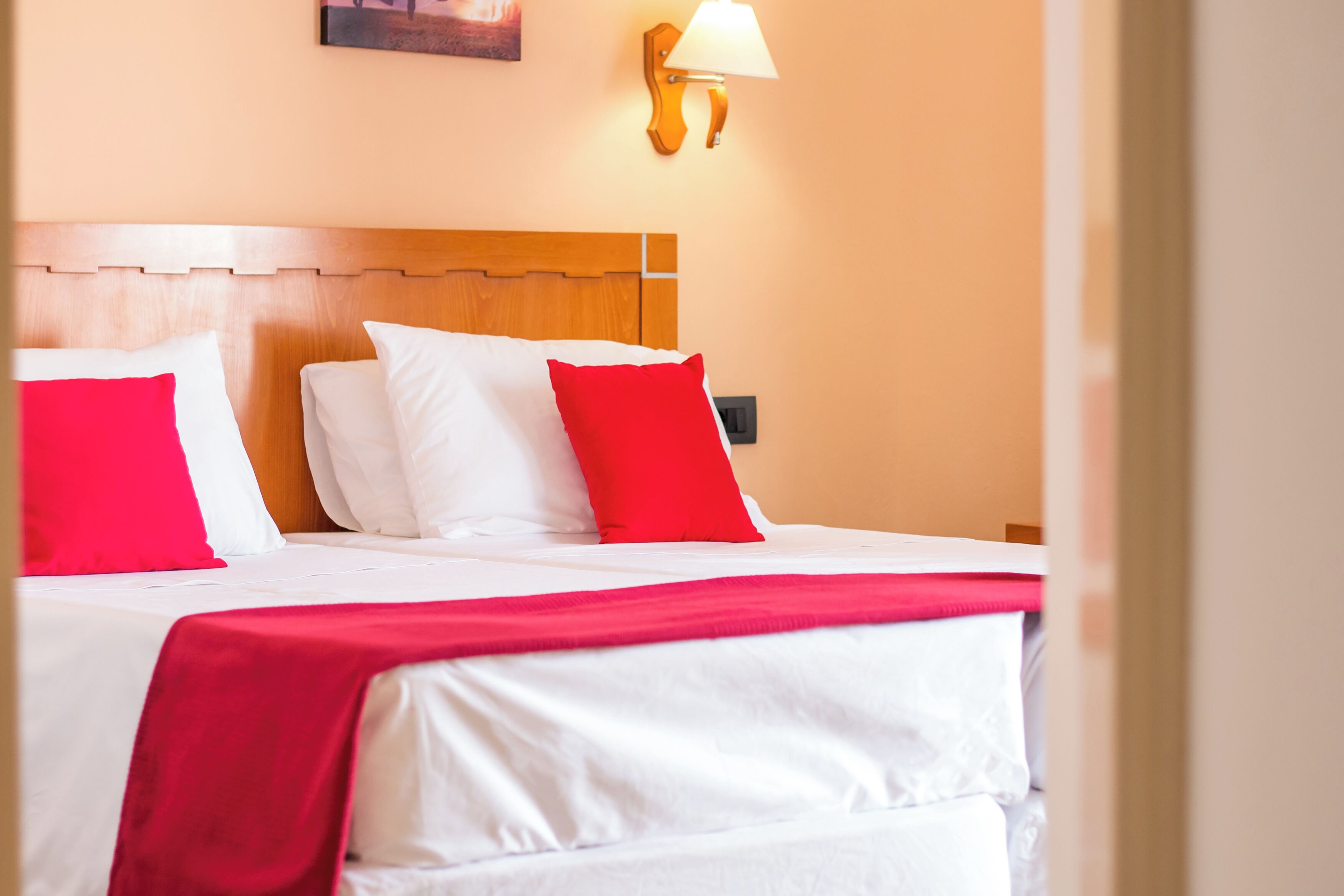 Ein Hotelzimmer mit Holz Kopfteil, weißer Bettwäsche und einem roten Zierkissen.