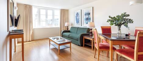Un salon moderne comprenant un canapé, une table à manger avec des chaises, une table basse et une grande fenêtre avec des rideaux.