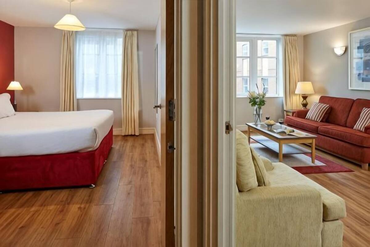 A hotel room with a bed, a sofa, a coffee table, and a window.