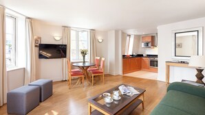 Una habitación de hotel moderna con comedor, kitchenette y un sofá verde.