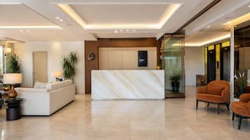 Um hall de hotel moderno com uma receção, área de estar e divisória de vidro.