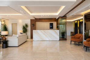 A modern hotel lobby with a reception desk, seating area, and a glass partition. - The Biancho Hotel Pera (Istanbul)
