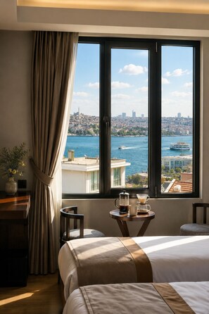A hotel room with a large bed, a coffee table with a coffee pot and cups, a view of a cityscape and water through a window. - The Biancho Hotel Pera (Istanbul)