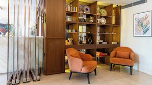 A room with a wooden bookshelf, two orange armchairs, and a large window with a view. - The Biancho Hotel Pera (Istanbul)