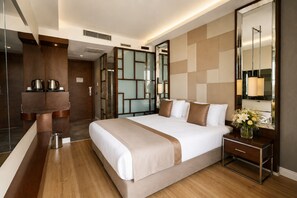 Habitación de hotel con una cama grande, mesita de noche, espejo y vistas a un pasillo.