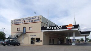 Un edifici amb un cartell d'alberg i cafeteria, i una gasolinera amb el logotip de Repsol.
