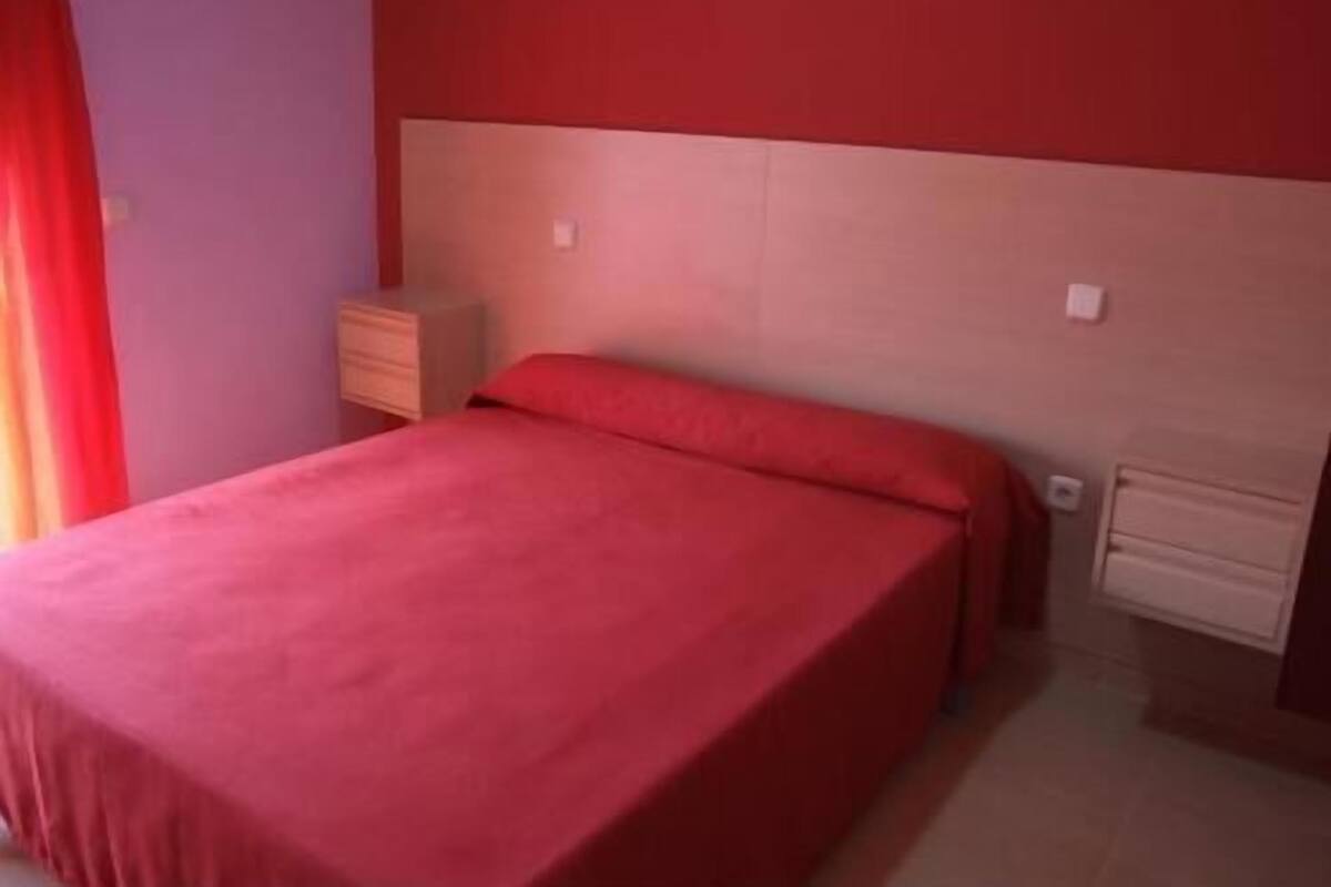 A bedroom with a bed, a nightstand, and a dresser.