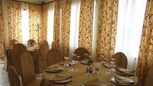 Zona de menjador amb taules rodones preparades per a sis persones, cobertes amb estovalls beix i envoltades per cadires amb fons marrons.