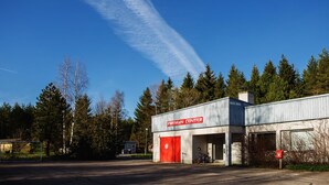 A building labeled "Fireman Center" with a red door, surrounded by trees and a clear sky.