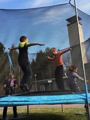 Ein Trampolin in einem Außenbereich mit einem Metall-Sicherheitsnetz darüber.