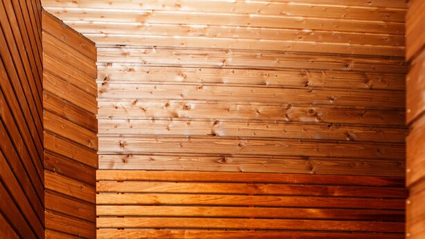 A wooden sauna with benches and a bucket.