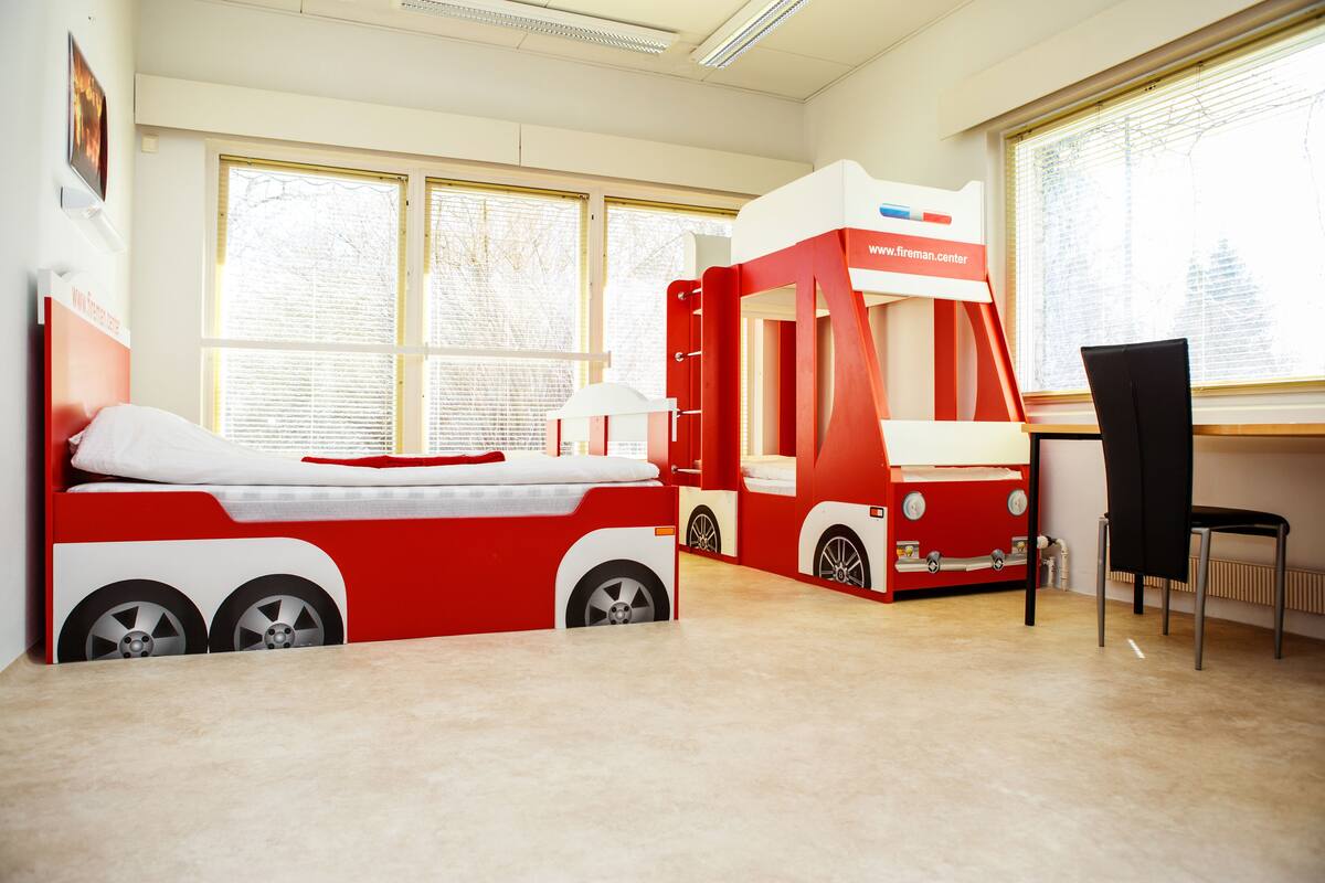 A child's bedroom with a red and white train-themed bed and a desk.