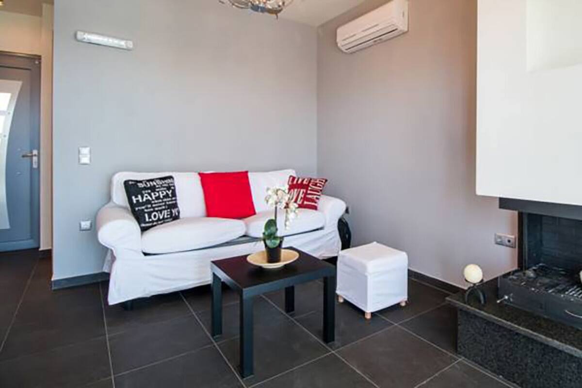 A modern living room with a white sofa, a small table, and a fireplace.