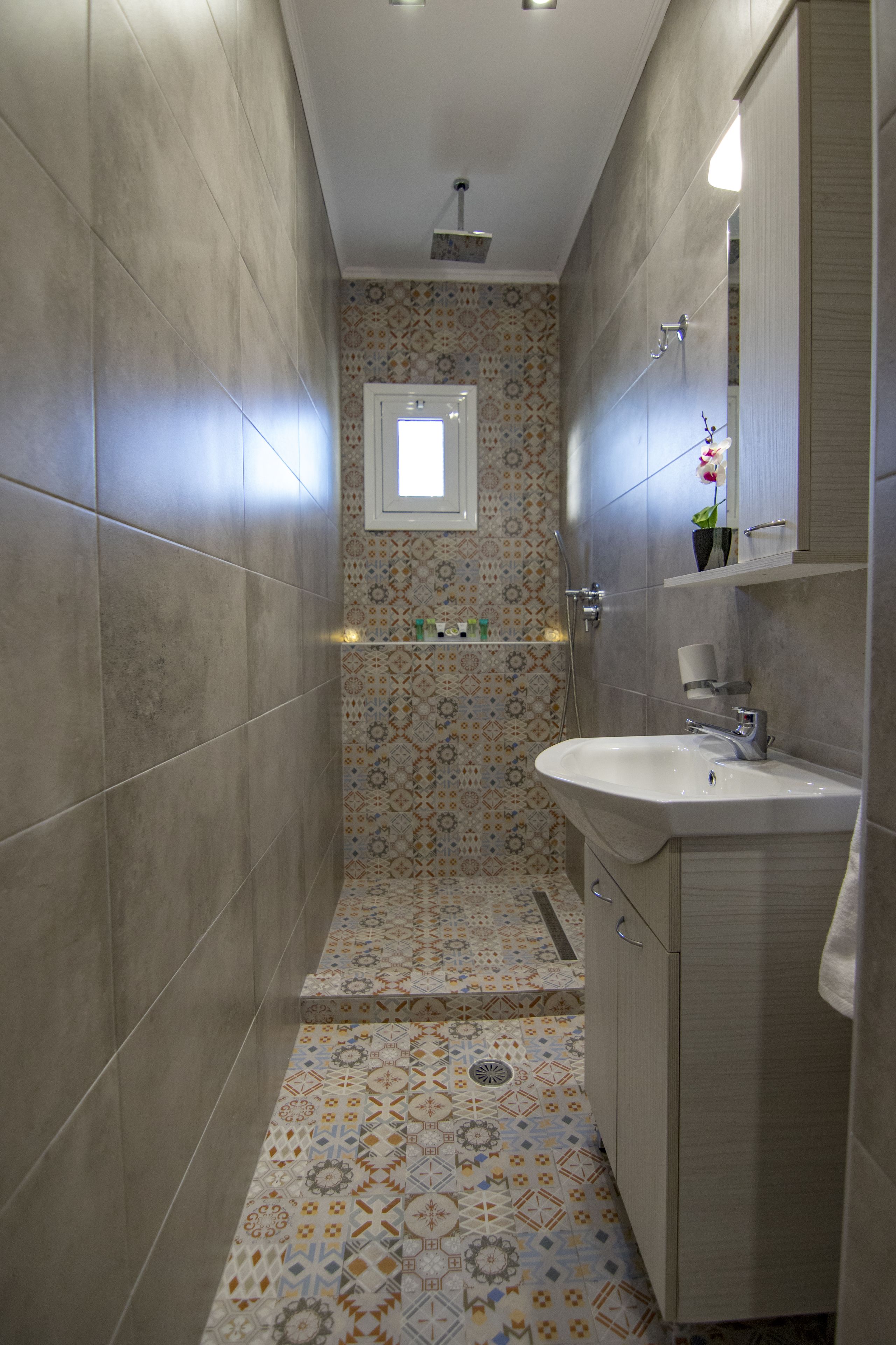 Une petite salle de bain avec des carreaux décorés, un lavabo et un miroir.
