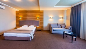 A hotel room with two beds, a sofa, a small table, and wall-mounted lights. - Zagrava Hotel (Dnipro)