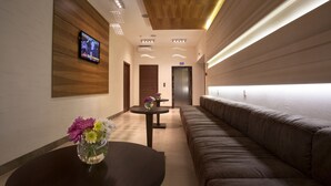 A modern hotel lobby with a wooden ceiling, a reception desk, a sofa, and a TV screen. - Zagrava Hotel (Dnipro)