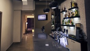 A modern bar area with a long counter, hanging lights, and a brick wall with shelves of bottles. - Zagrava Hotel (Dnipro)