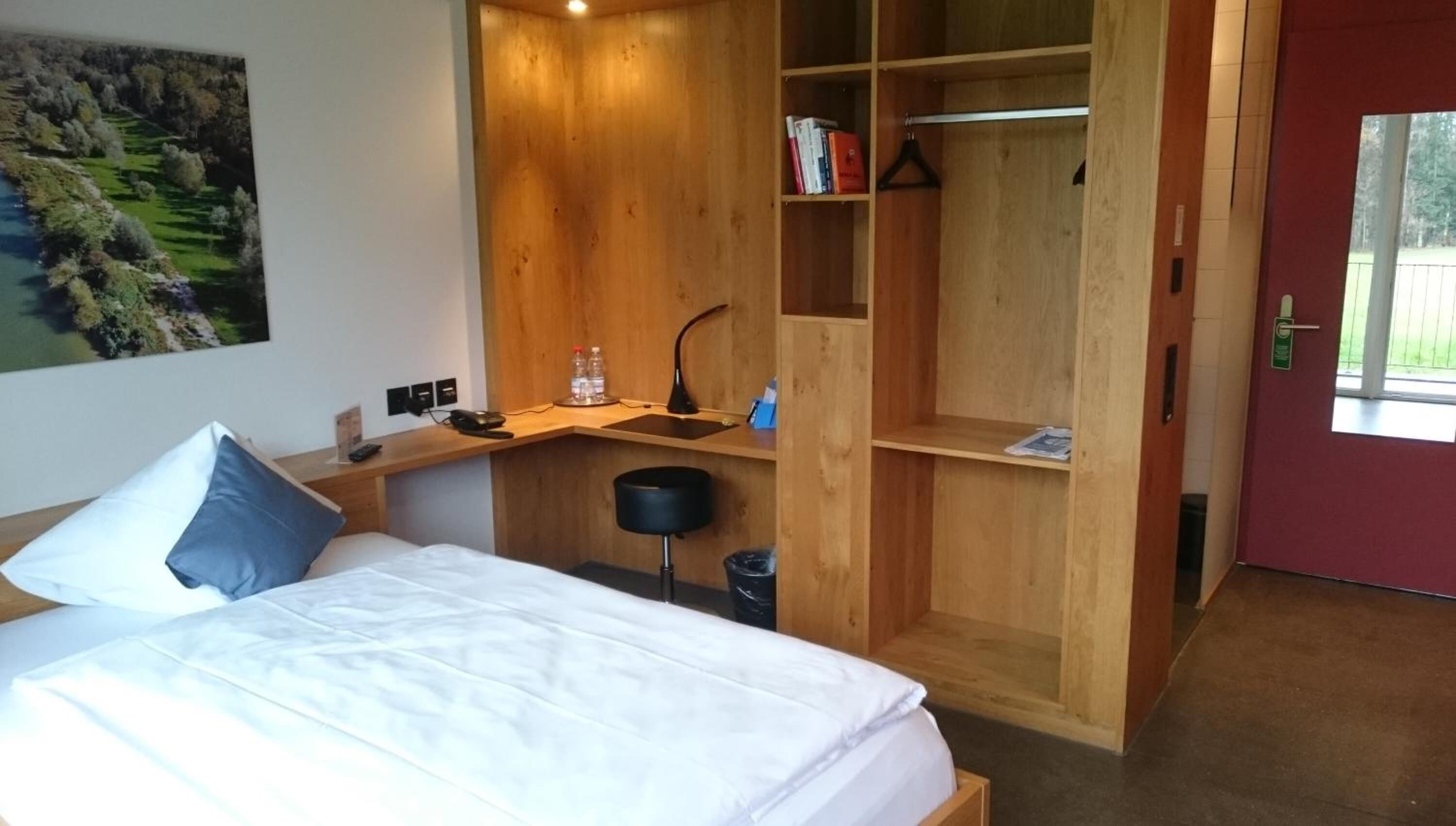 Een slaapkamer met een bed, een bureau, een stoel, een kledingkast en een raam.