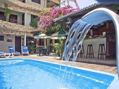 Una piscina al aire libre, sombrillas, sillones reclinables de piscina