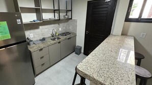 Cozinha moderna com bancadas de granito, eletrodomésticos de aço inoxidável e uma porta preta.