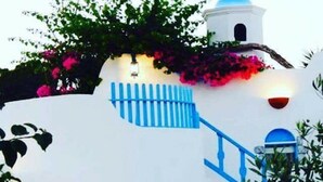 Un edificio bianco con dettagli blu, un campanile e una scala.