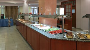 Un buffet con diversi cibi, un bambino e un addetto alla ristorazione.