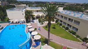 Una piscina circondata da lettini e ombrelloni, con un edificio sullo sfondo.