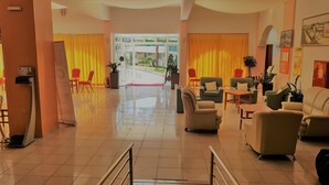 Una hall d'albergo con reception, zona salotto e vista sull'esterno.