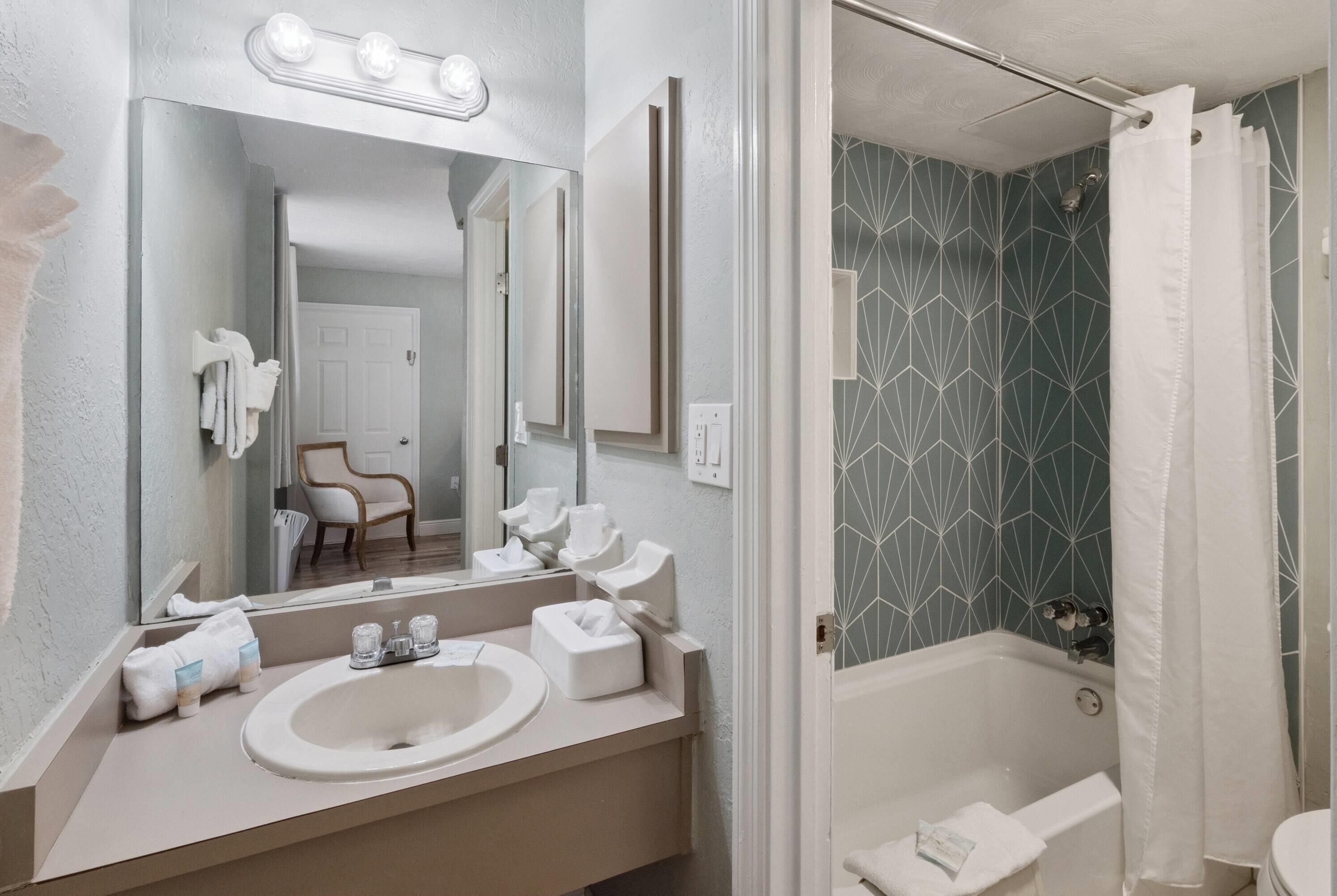 A bathroom with a sink, mirror, and shower.