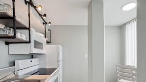 Una cocina moderna con electrodomésticos blancos, un lavamanos de acero inoxidable y un ventanal que proporciona luz natural.