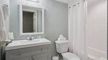 Un baño con lavamanos, espejo, inodoro y cortina de ducha.
