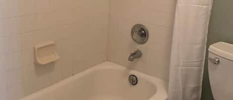 Un baño con bañera, inodoro y cortina de ducha.