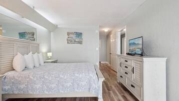 Un dormitorio con cama, cómoda, televisor y un cuadro en la pared.