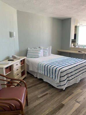 Quarto com cama, mesa de cabeceira, cadeira e espelho.