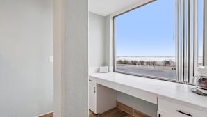 Cocina moderna con un ventanal grande, muebles blancos y vistas a la playa.