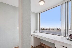 A modern kitchen with a large window, white cabinetry, and a view of the beach. - Howard Johnson by Wyndham Oceanfront Daytona Beach (Daytona Beach)