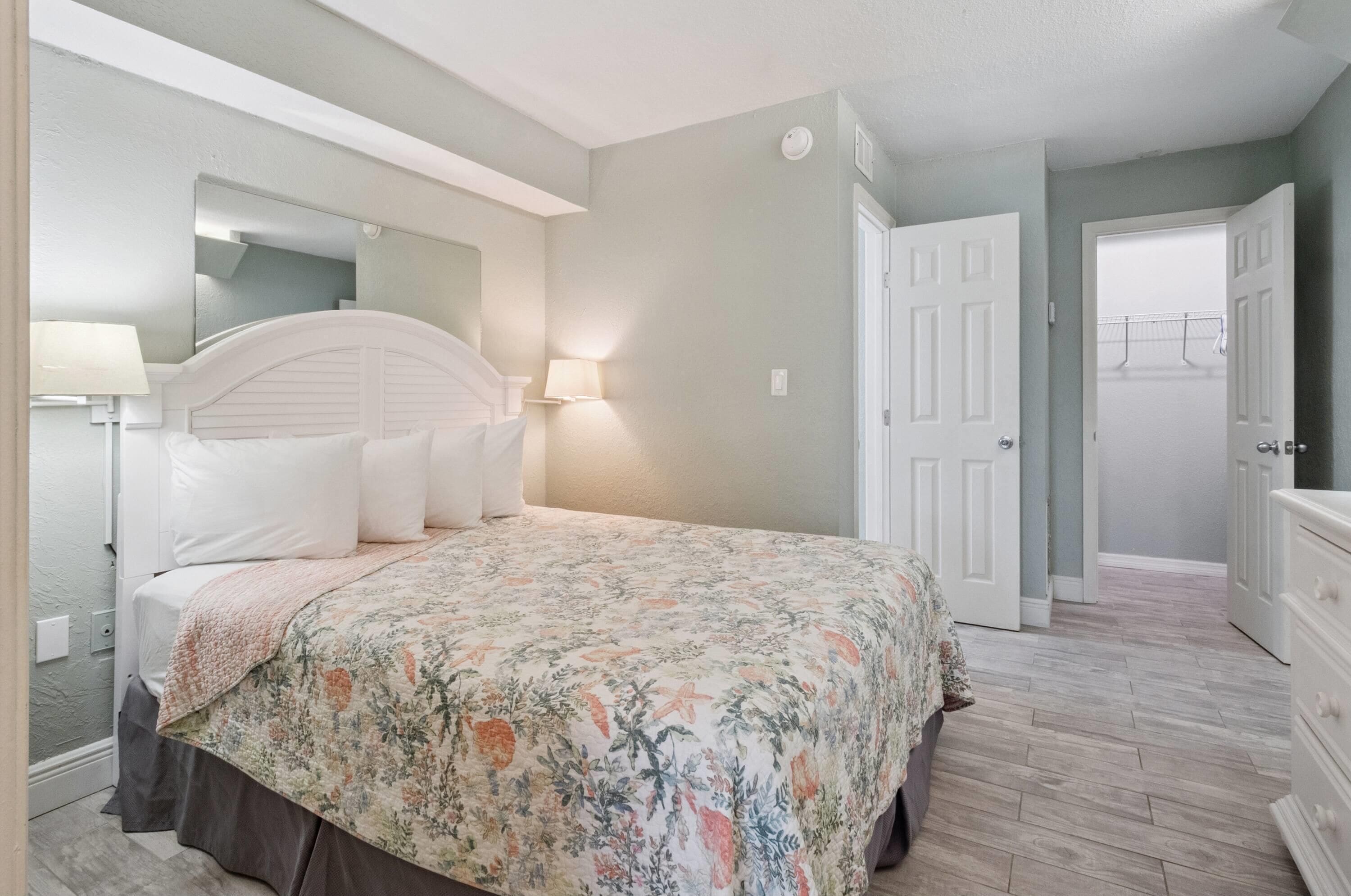 A bedroom with a bed, bedside lamps, a dresser, and a door.